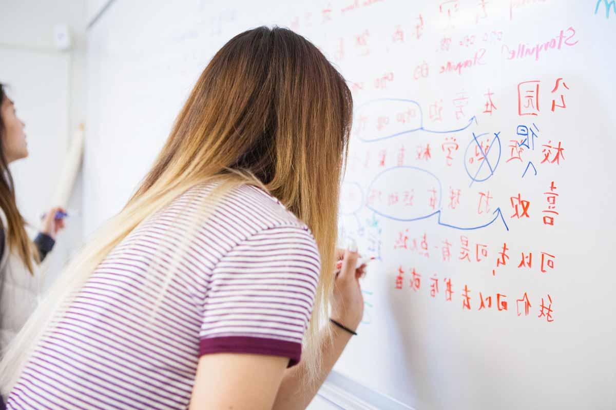 Students writing Mandarin on a white board